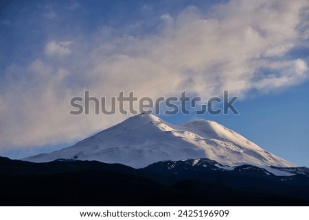 Russia Caucasus, Mount Elbrus towers majestically, adorned in pristine snow and ice. Alpine landscape boasts panoramic views of rugged ridges, serene valleys, and icy glaciers under the vast blue sky Royalty-Free Stock Photo #2425196909