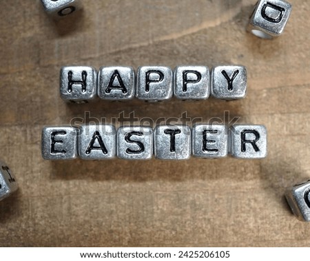 The image is a sign on a wooden wall that reads "Happy Easter." It is outdoors.