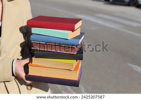 a woman holding a stack of books in her hands