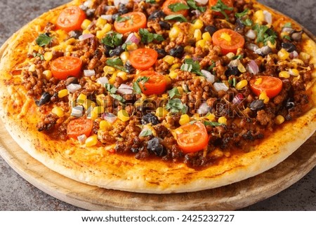 Hot Tex Mex taco pizza with ground beef, salsa, cheddar cheese and Mexican spices close-up on a wooden board on the table. Horizontal
