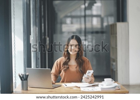 Beautiful young concentrated business woman wearing shirt using laptop while standing in modern workspace