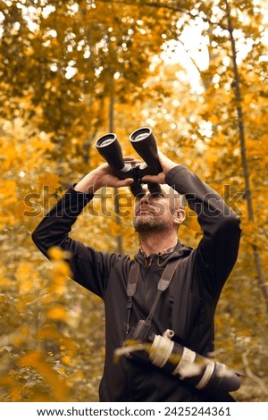 Man using binoculars for birdwatching and other observing animals in nature. Royalty-Free Stock Photo #2425244361