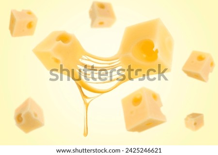 Pieces of cheese falling on yellow background Royalty-Free Stock Photo #2425246621