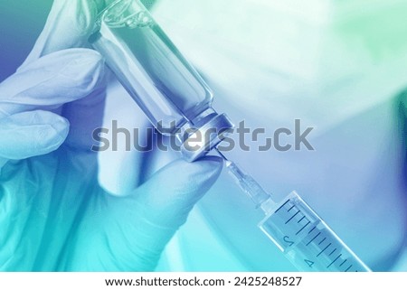 Doctor filling syringe with medication from vial, closeup. Color toned Royalty-Free Stock Photo #2425248527
