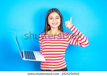 Beautiful attractive Young kid girl wearing striped t-shirt  hold netbook hand finger show thumb up