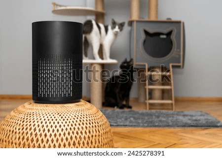 air purifier in the area with pets or cat. Air Pollution Concept. Air purifier, filters out invisible viruses, allergens or pollutants in the house on a cat tree background. Cute cat and Air purifier Royalty-Free Stock Photo #2425278391