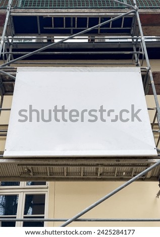 Scaffolding banner with space for banner advertising on the house facade Royalty-Free Stock Photo #2425284177