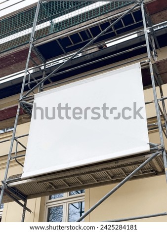 Scaffolding banner with space for banner advertising on the house facade Royalty-Free Stock Photo #2425284181