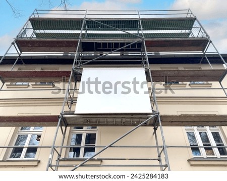 Scaffolding banner with space for banner advertising on the house facade Royalty-Free Stock Photo #2425284183