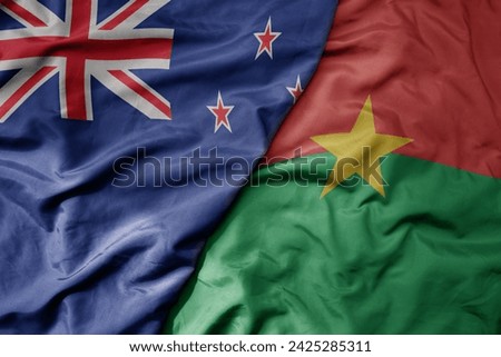 big waving national colorful flag of burkina faso and national flag of new zealand . macro