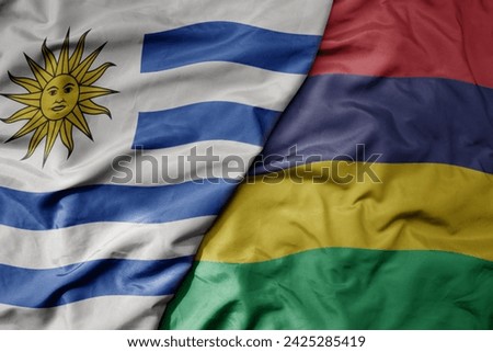 big waving national colorful flag of mauritius and national flag of uruguay . macro