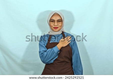 young Asian Muslim woman wearing hijab, glasses and brown apron, open sign to greet and greet customers isolated on white background. People housewife muslim lifestyle concept
