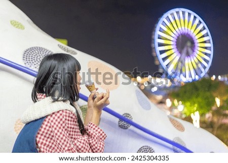 A young Taiwanese woman in her 20s who eats sweets at night at an amusement park in Shilin District, Taipei City, Taiwan