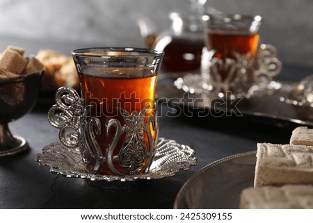 Turkish tea and sweets served in vintage tea set on black table, closeup