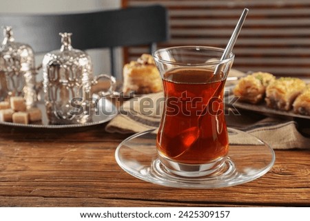 Glass of traditional Turkish tea and sweets served in vintage tea set on wooden table