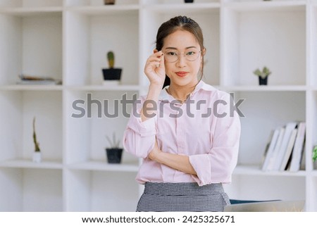 Happy asian young businesswoman arms crossed standing in office working space.