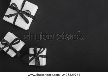 White gift boxes with black ribbons on a dark black background with space for text. Congratulations, card.