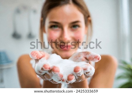blond girl blowing on foam in her hand, young woman showing hands in foam, happy beautiful young woman face wash, 