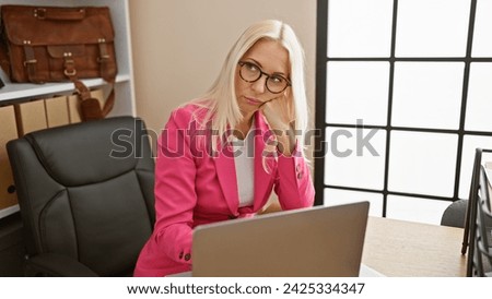 Exhausted young caucasian woman working a boring job, lost in her laptop at the office, a blonde business worker portrait