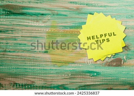 Stack of note paper with 'Helpful tips' text on a wooden background. Tips and advice concept
