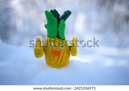 A toy pineapple made of plasticine on a background of snow.