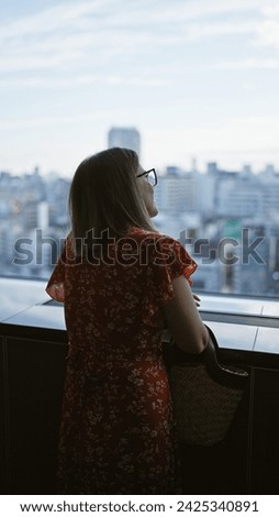 Beautiful hispanic businesswoman in glasses, captivating cityscape view from skyscraper window in japan's urban skyline