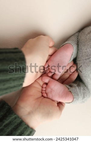 The palms of the father, the mother are holding the foot of the newborn baby. Feet of the newborn on the palms of the parents. Studio macro photo of child's toes, heels and feet on a white background.