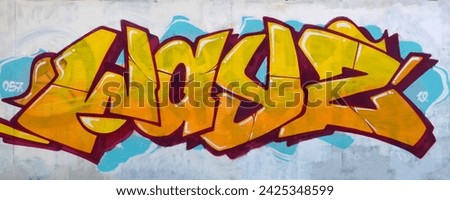 The old wall decorated with paint stains in the style of street art culture. Colorful background of full graffiti painting artwork with bright aerosol outlines on wall. Colored background texture Royalty-Free Stock Photo #2425348599