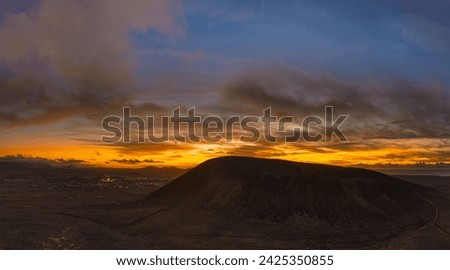 Stunning sun set image over Volcan Calderon Hondo volcanic crater silhouetted against the setting sun and skyscape near Corralejo, Fuerteventura, Canary Islands, Spain