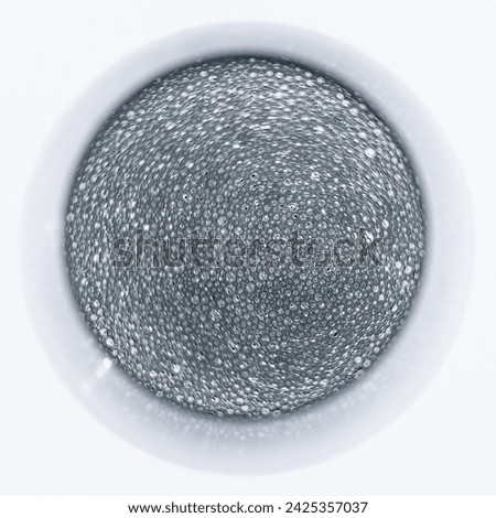 Artistic abstract top to bottom picture of round glass full of sparkling wine with rotating blurred tiny bubbles on its surface 
