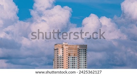 High section of modern skyscraper hotel against big rain clouds on blue sky background before raining. Cityscape panoramic view in street minimal style Royalty-Free Stock Photo #2425362127