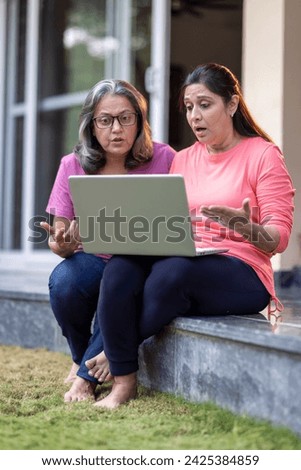 Portrait of an Elderly Woman and her Daughter Using Laptop Computer at backyard