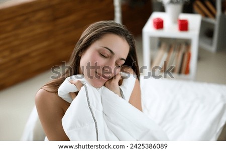 Girl sitting on white bed with closed eyes resting. Relaxation comfortable pleasant bed in your home. Improve sleep quality feel fresh, alert and full energy. Rest during self-isolation in apartment Royalty-Free Stock Photo #2425386089