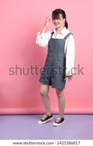Cheerful lovely young asian woman in overalls casual clothes with gesture of Stress isolated on pink background. St Valentine's Day, Women's Day, Birthday