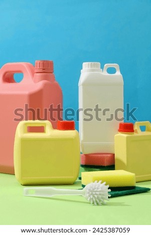 Front of plastic canisters with different sizes and colors decorated on blue background with cleaning tools. Mockup canister empty label for design. Household cleaning chemicals. Chemical substances