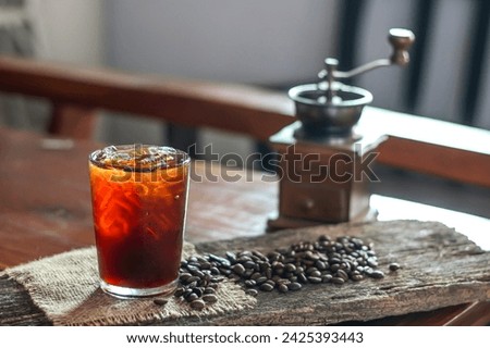 Pictures of Americano ice coffee and coffee grinder put on the table and old wooden with concept photo of coffee maker.