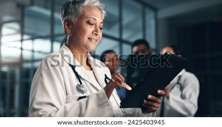 Doctor, mature woman and happy with tablet in night, typing or smile for results, meme or notification in hospital. Senior nurse, digital touchscreen or funny video with click, scroll or social media