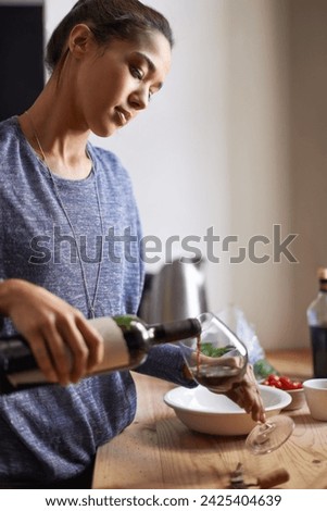 Woman, pouring red wine and home for dinner, relax for peace and leisure with drink in kitchen. Alcohol, glass and bottle with refreshment, hydration with beverage to celebrate or chill in apartment Royalty-Free Stock Photo #2425404639