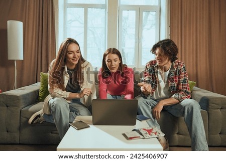 Live discussion. Young people, men and women, friends sitting on couch at home and booking trip online via laptop. Choosing transport and hotels. Concept of vacation, traveling, booking services