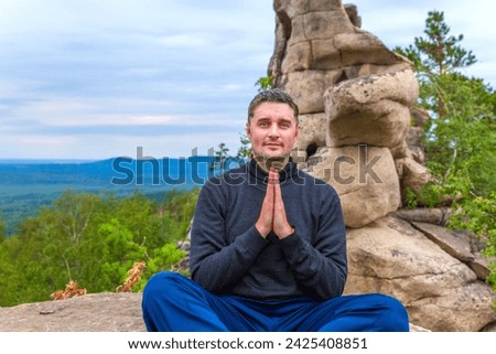 young handsome man on a rock on the Arakul shihan enjoys on a summer day Royalty-Free Stock Photo #2425408851