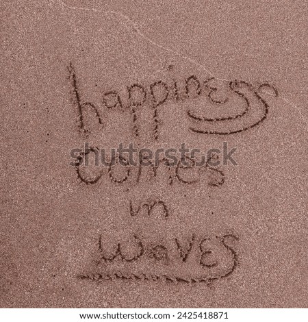 happiness comes in waves a true quotes written on golden sand of a moroccan beach.
