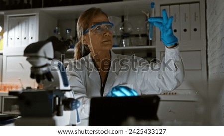 A mature woman scientist examines a test tube in a well-equipped indoor laboratory, highlighting research and analysis.
