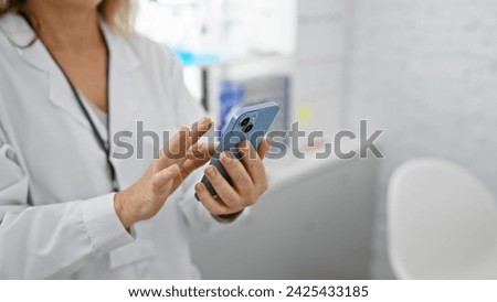 Caucasian woman healthcare professional using smartphone in laboratory setting Royalty-Free Stock Photo #2425433185