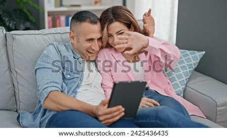 Man and woman couple having video call sitting on sofa at home
