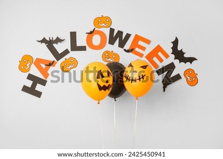 Word HALLOWEEN with balloons and paper decor on white background