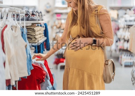 Expectant mother joyfully selects adorable clothes for her unborn baby while enjoying a shopping spree in the vibrant aisles of the shopping center Royalty-Free Stock Photo #2425451289