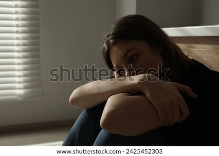 Sad young woman sitting indoors, space for text