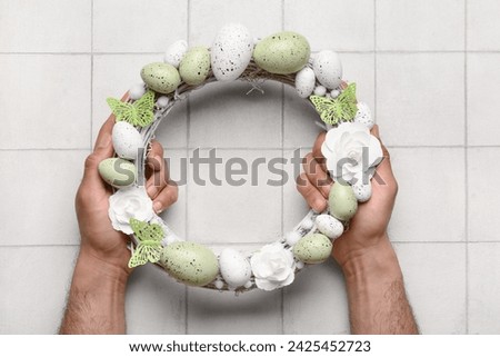 Man holding Easter wreath on white tile table