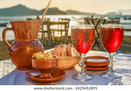 A pitcher and 2 glasses of sangria with side dishes in a Mediterranean restaurant at sunset Royalty-Free Stock Photo #2425452895