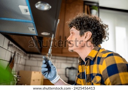 Latino man fixing aspirator in the kitchen. Royalty-Free Stock Photo #2425456413